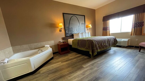 Habitación de hotel con una cama grande, baño privado con bañera, escritorio y ventana con cortinas.