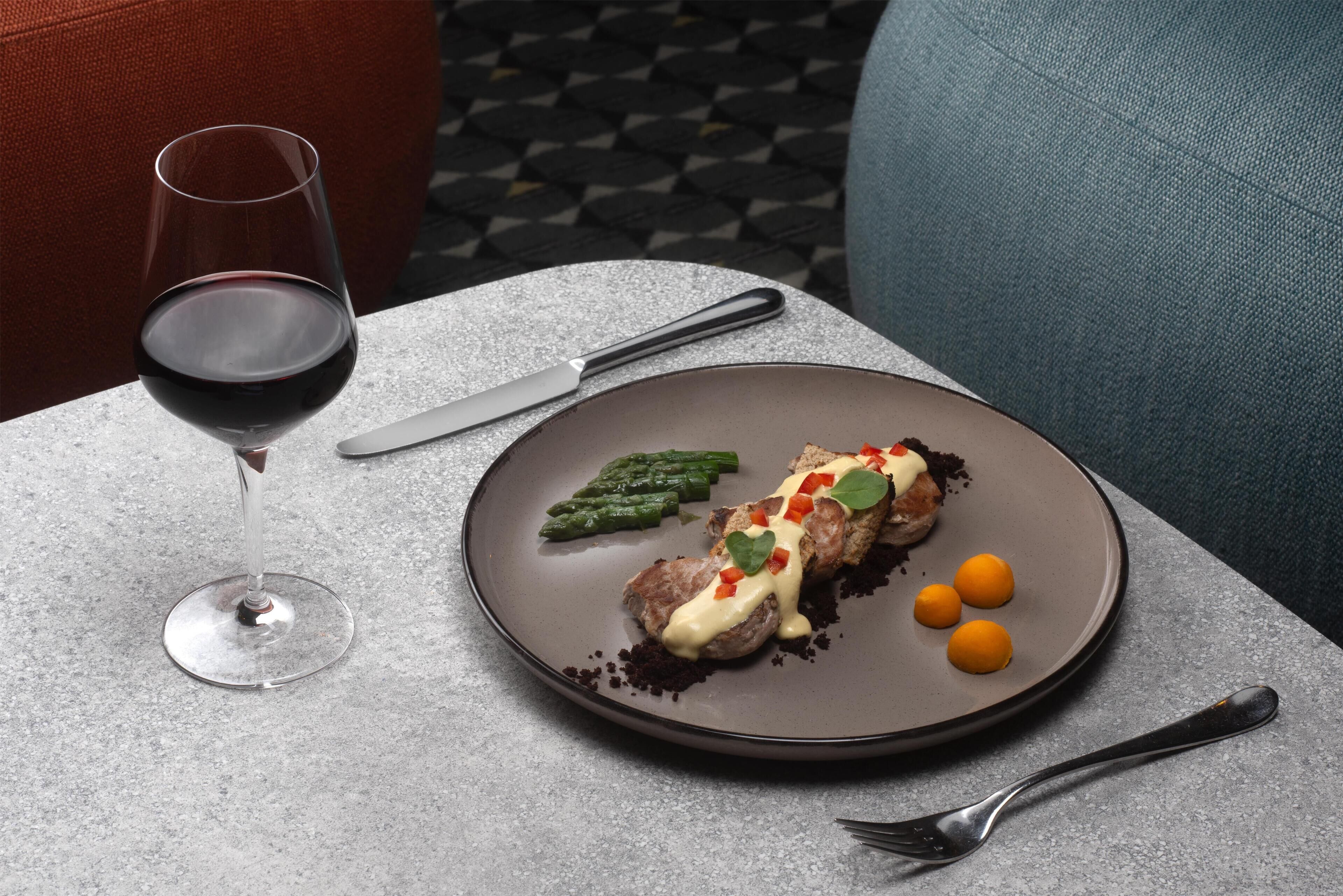 A dining table with a plate of food, a wine glass, and cutlery.