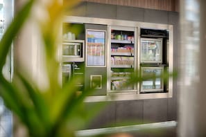 Un kiosque en libre-service doté de compartiments réfrigérés, probablement pour les boissons et les en-cas, situé dans un environnement moderne.