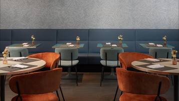 A restaurant with booths and round tables, each with a vase of flowers and a menu.