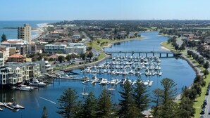 A marina with numerous boats docked, a bridge crossing a river, and surrounding residential and commercial buildings.
