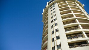 A tall, multi-story building with balconies and large windows.
