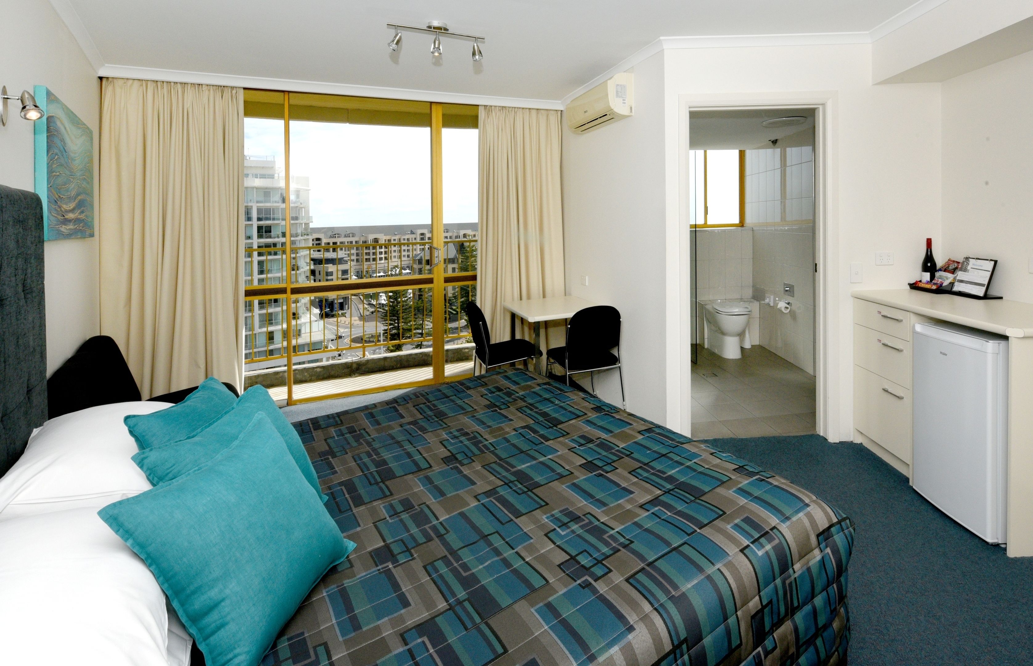Ein Hotelzimmer mit einem großen Bett, einem Schreibtisch und Blick auf die Stadt.