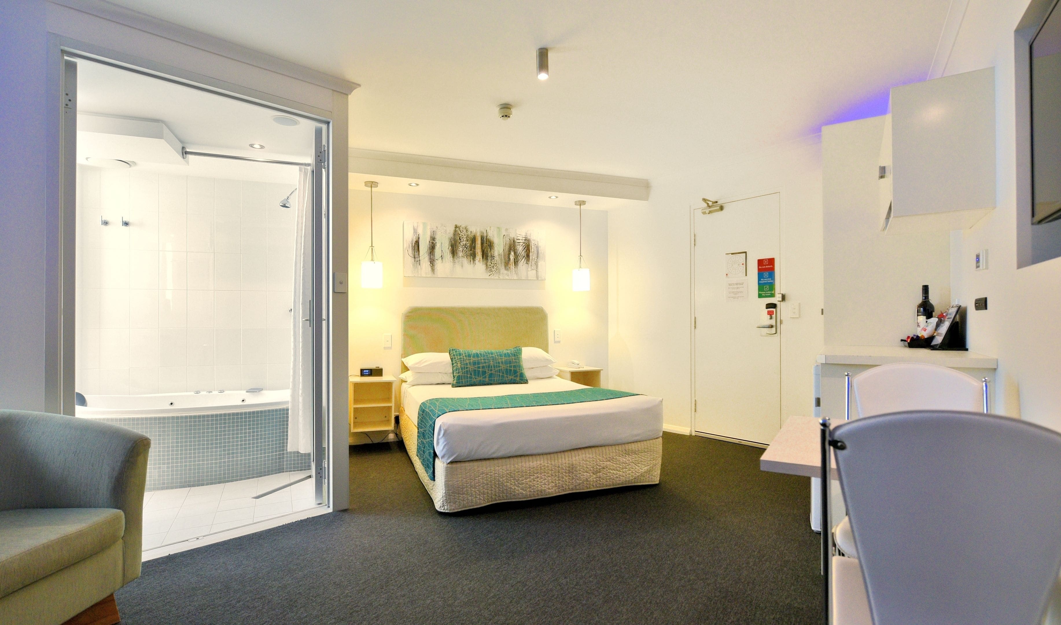 A hotel room with a bed, a shower, a desk, and a chair.
