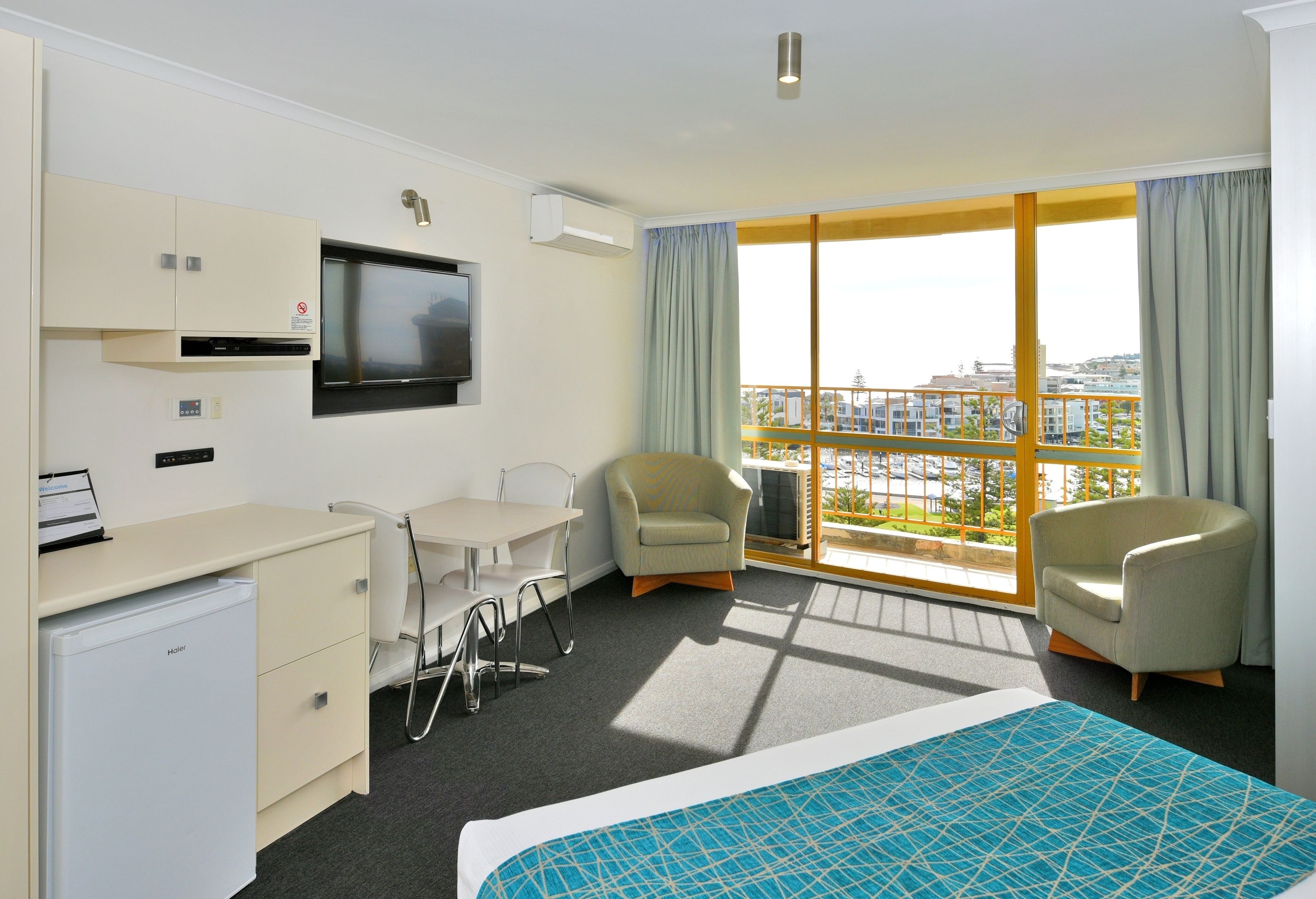 A hotel room with a bed, a desk, a chair, a TV, and a balcony with a view.