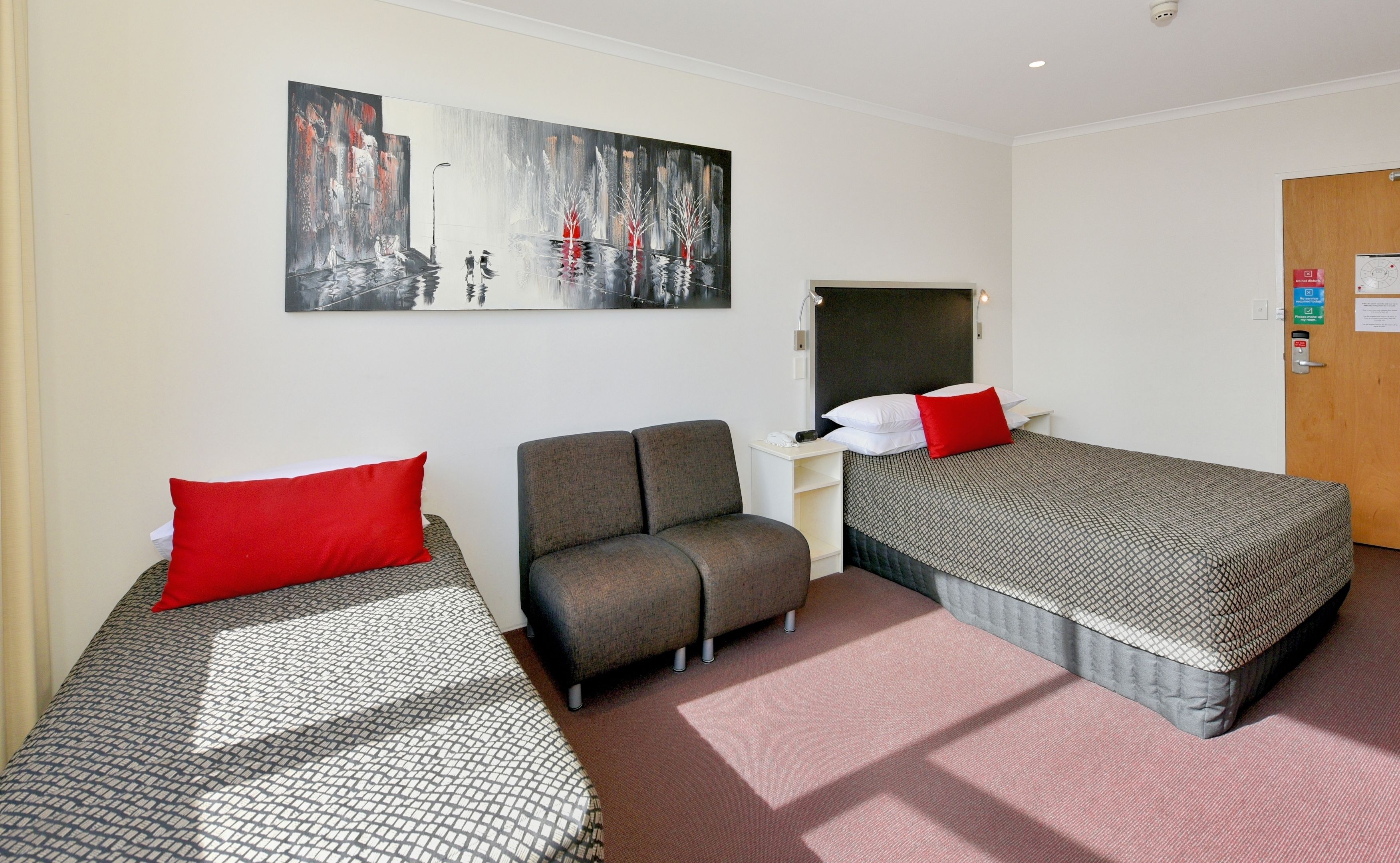 A hotel room with two beds, a sofa, a desk, and a painting on the wall.