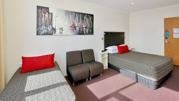 Habitación de hotel con dos camas, un sofá, un escritorio y un cuadro en la pared.