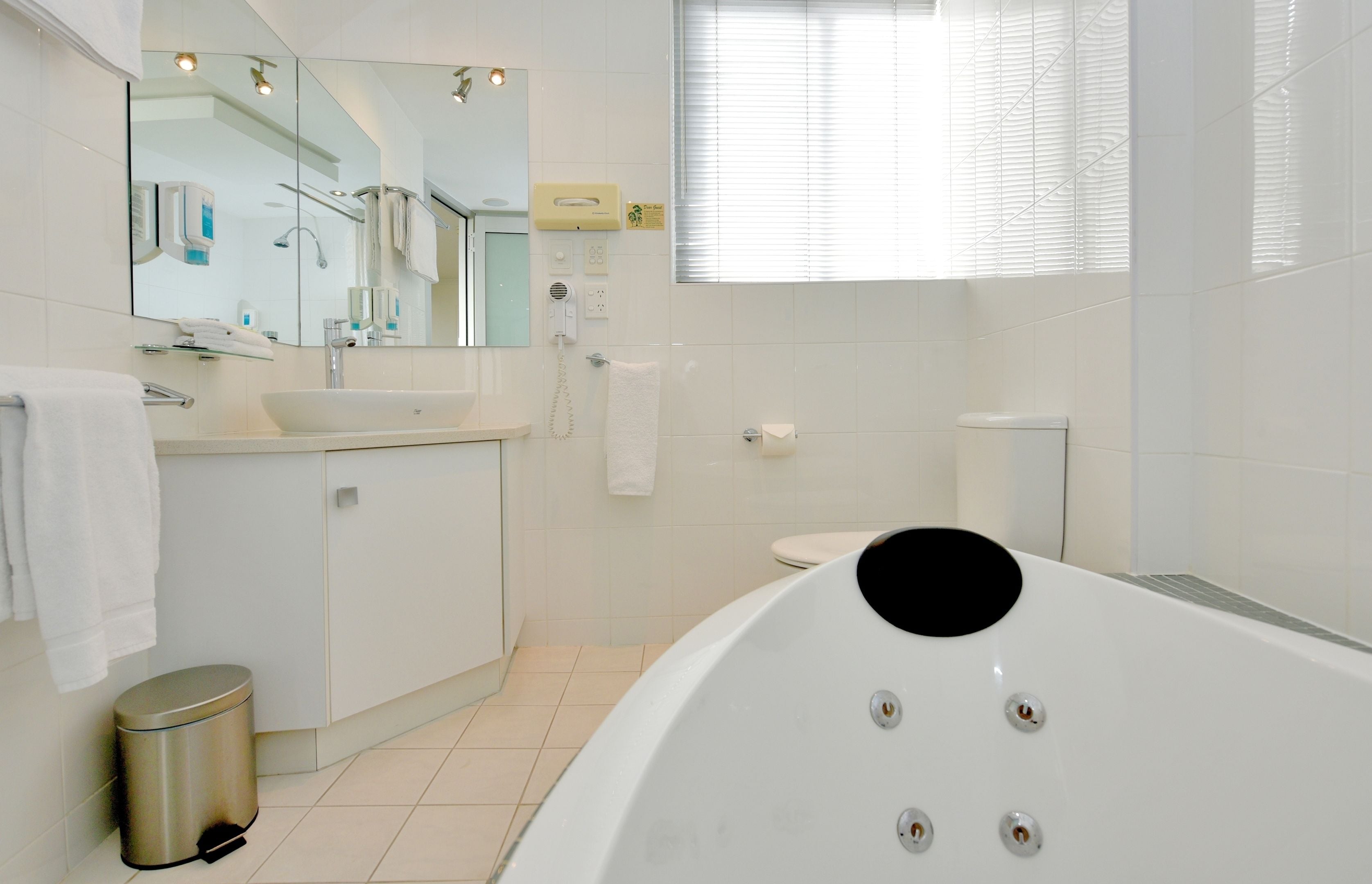 Un baño moderno con una bañera grande, un lavamanos, un inodoro y un cubo de basura.