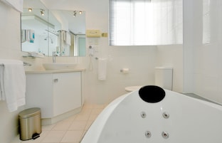 Un baño moderno con una bañera grande, un lavamanos, un inodoro y un cubo de basura.