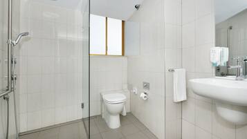A modern bathroom with a glass-enclosed shower, a toilet, and a sink with a mirror.