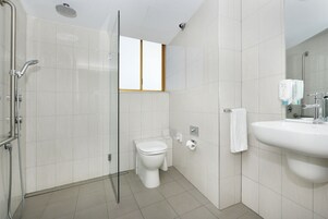 Un baño moderno con ducha de vidrio, inodoro y lavabo con espejo.