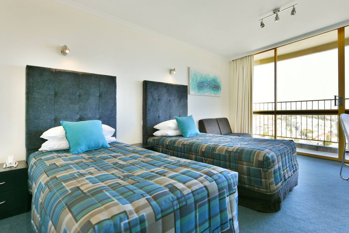 Ett hotellrum med två sängar, ett skrivbord och ett stort fönster med utsikt.