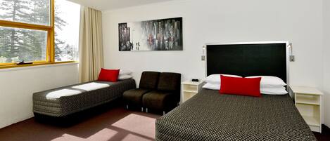 Une chambre d’hôtel avec deux lits simples, un canapé, un tableau au mur et une fenêtre avec des rideaux.