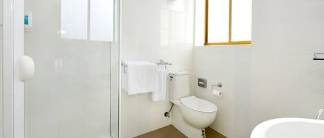 Un baño moderno con cabina de ducha de vidrio, inodoro y bañera.