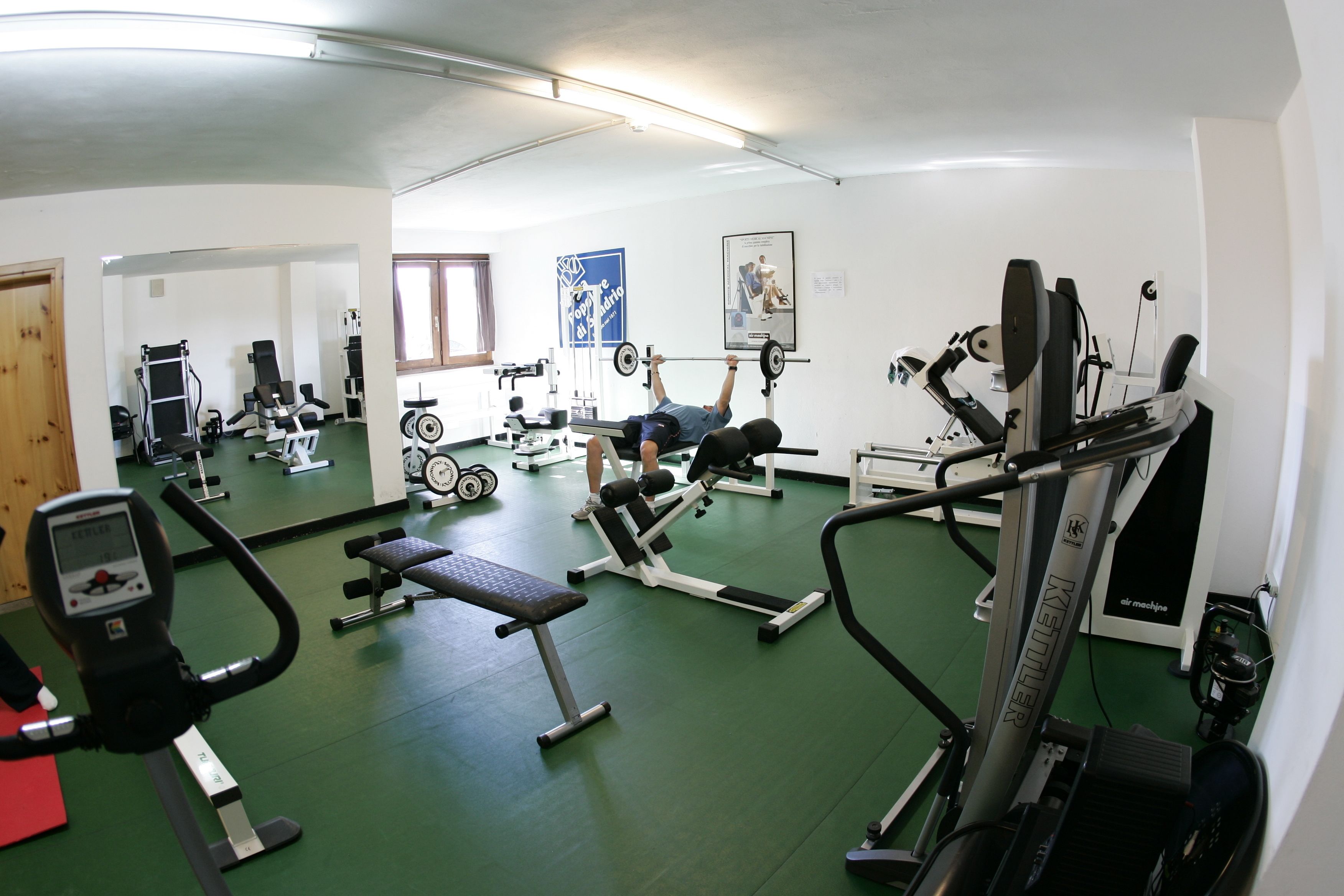 A gym with various exercise equipment, including treadmills, weight machines, and free weights.