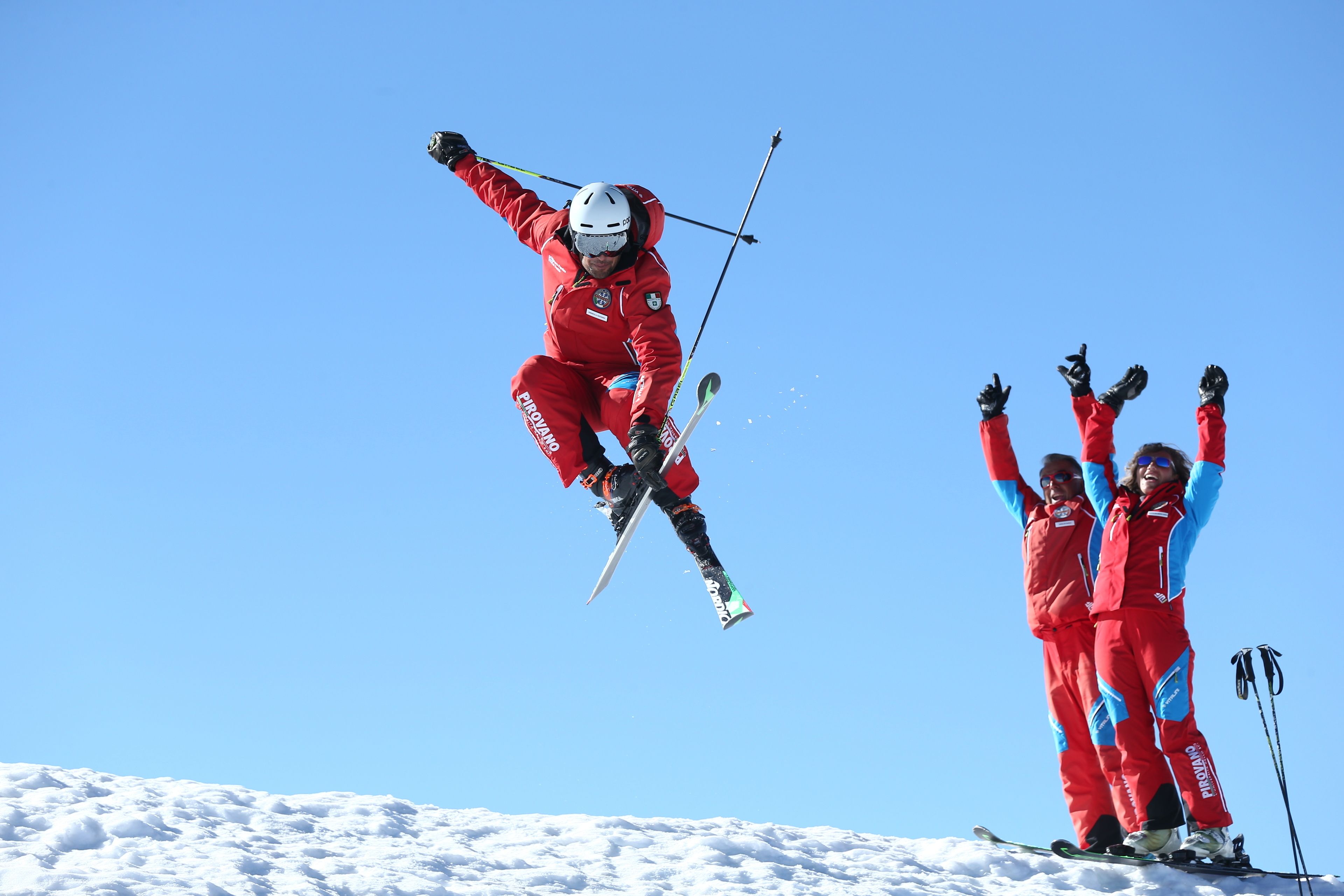 A ski jumper in mid-air with a clear blue sky in the background.