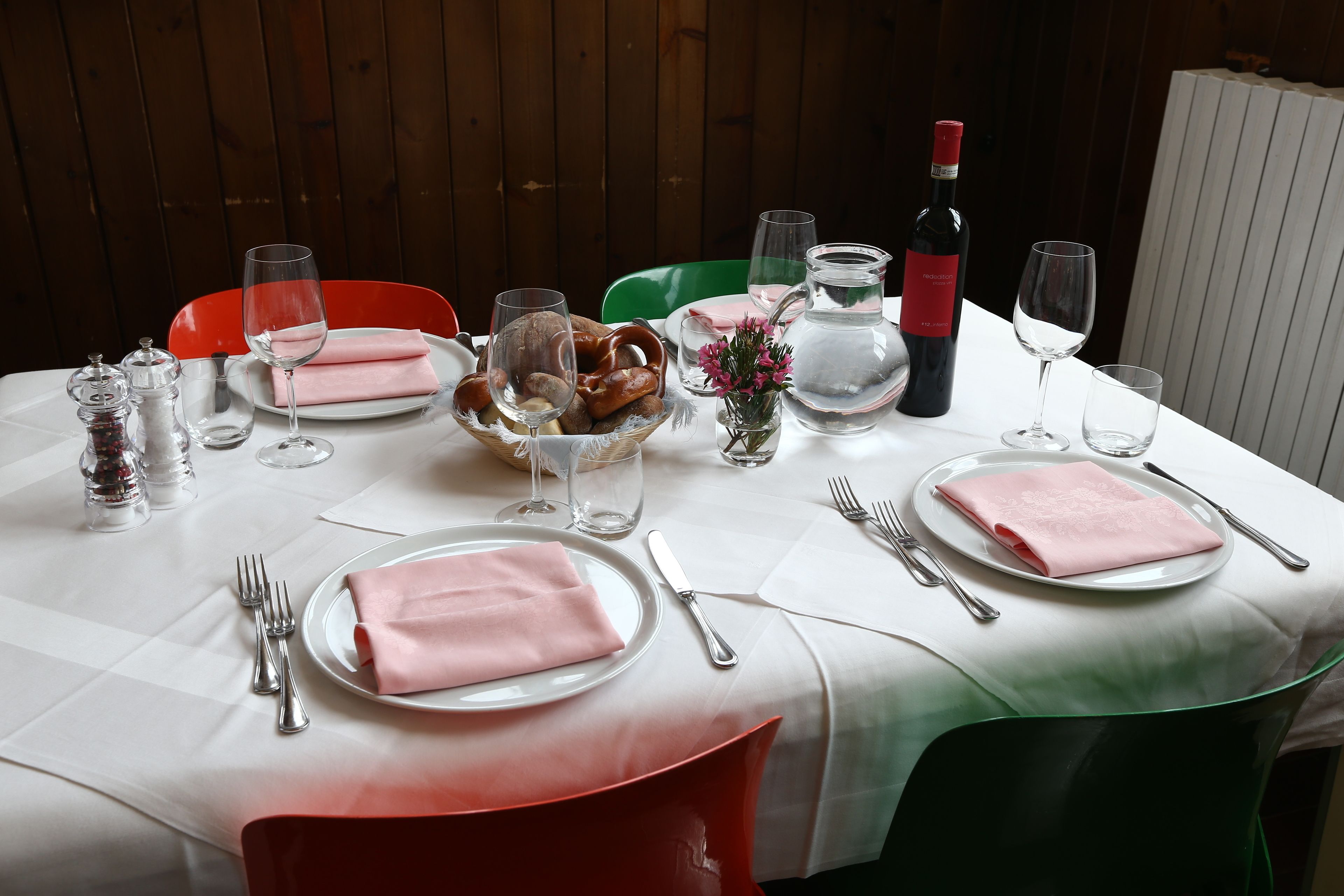 A table set for a meal with plates, cutlery, glasses, and a bottle of wine.