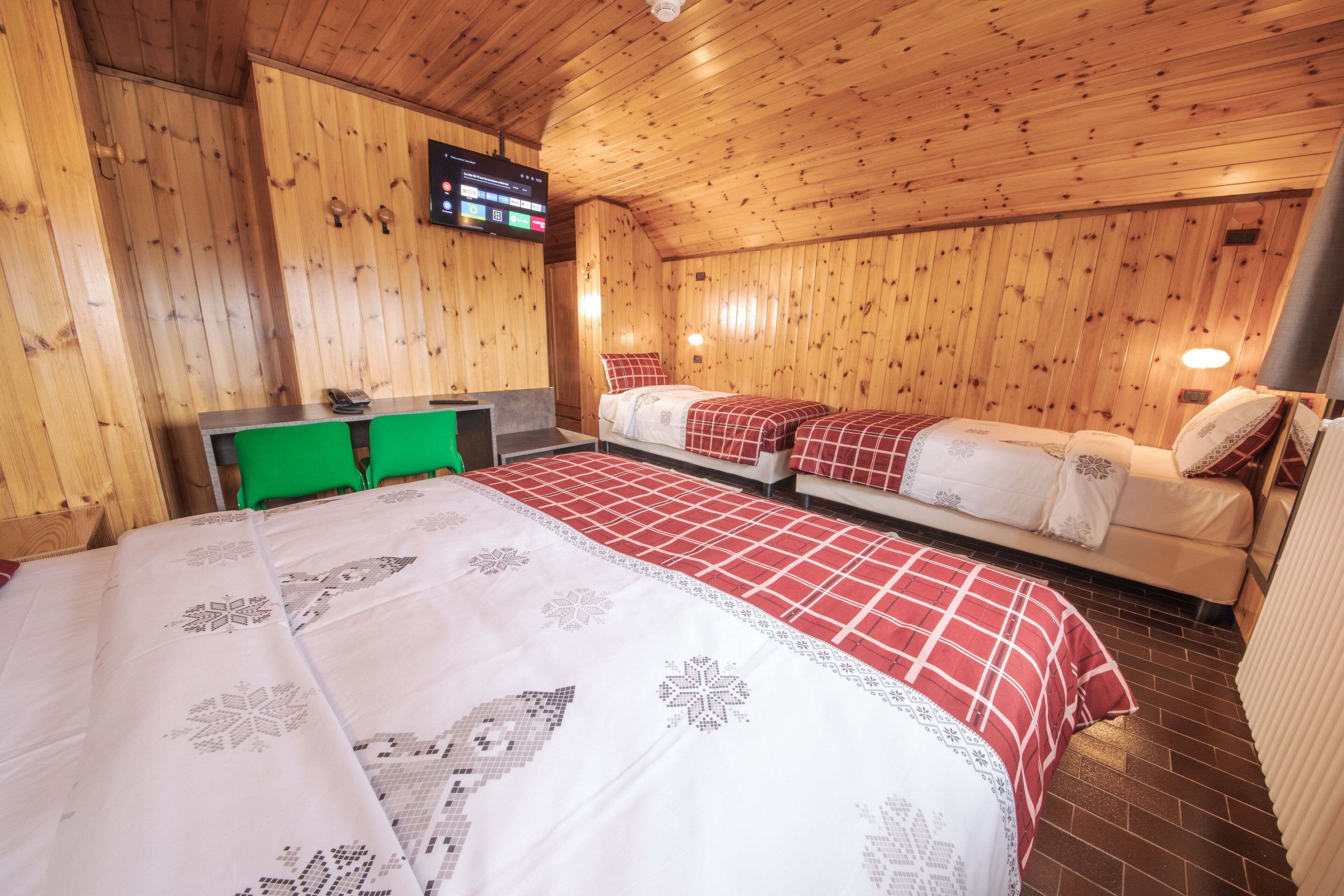 Una habitación con paneles de madera, una cama, dos sofás, un escritorio y un televisor.
