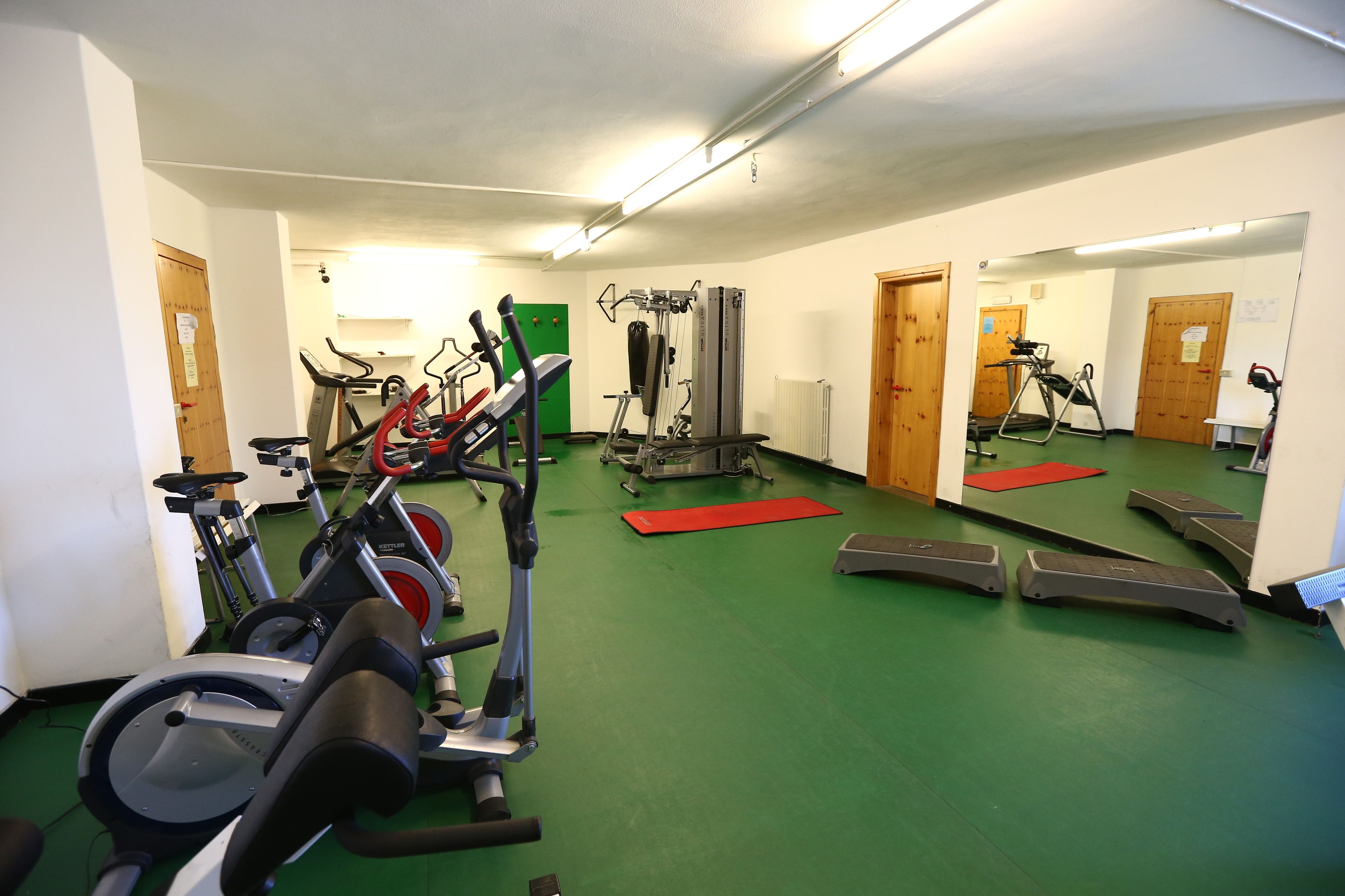 Un gimnasio con cintas de correr, elípticas y equipo de pesas.