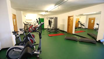 Un gimnasio con cintas de correr, elípticas y equipo de pesas.