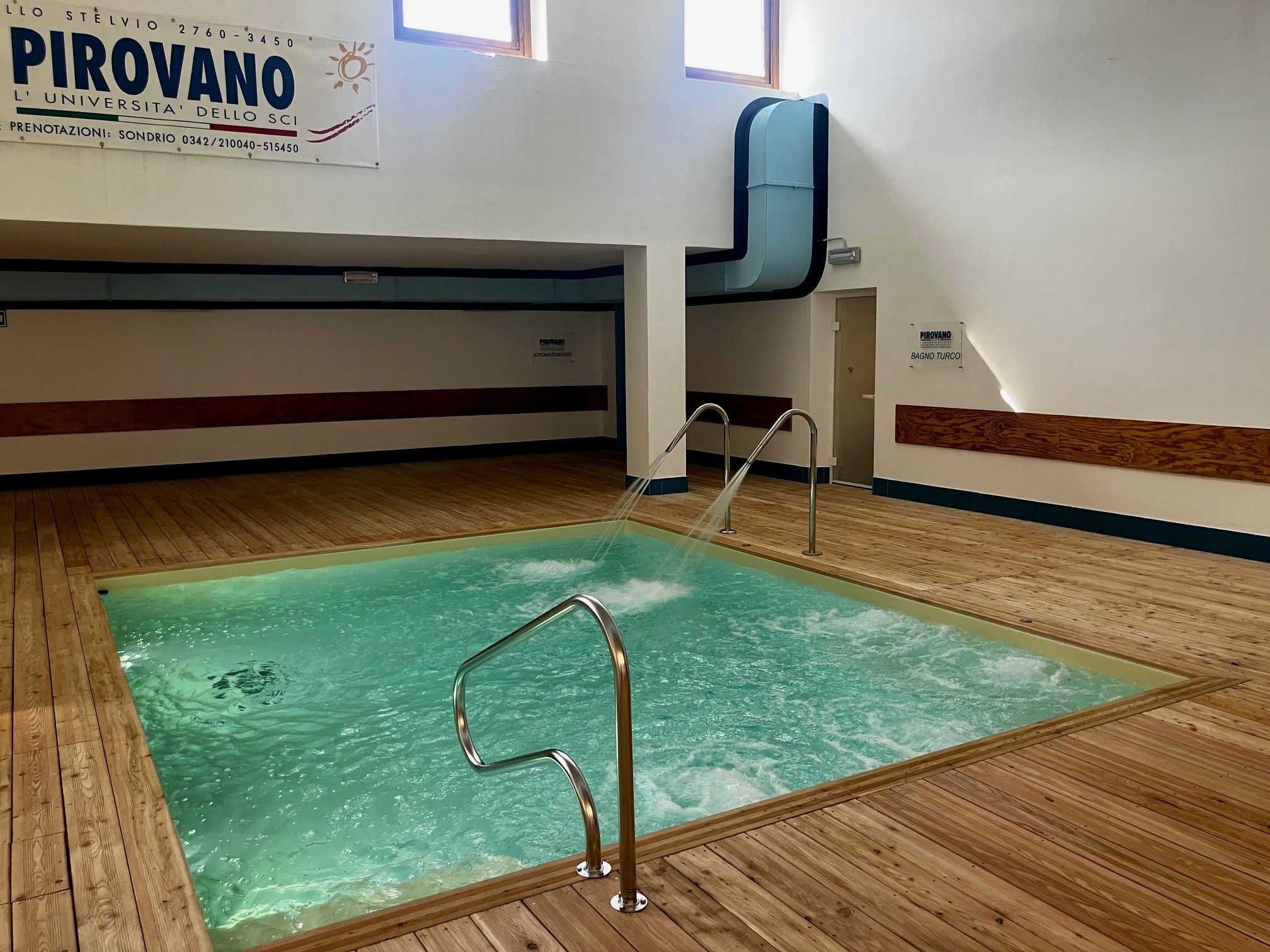 A swimming pool with a metal ladder, wooden deck, and a sign indicating the location.