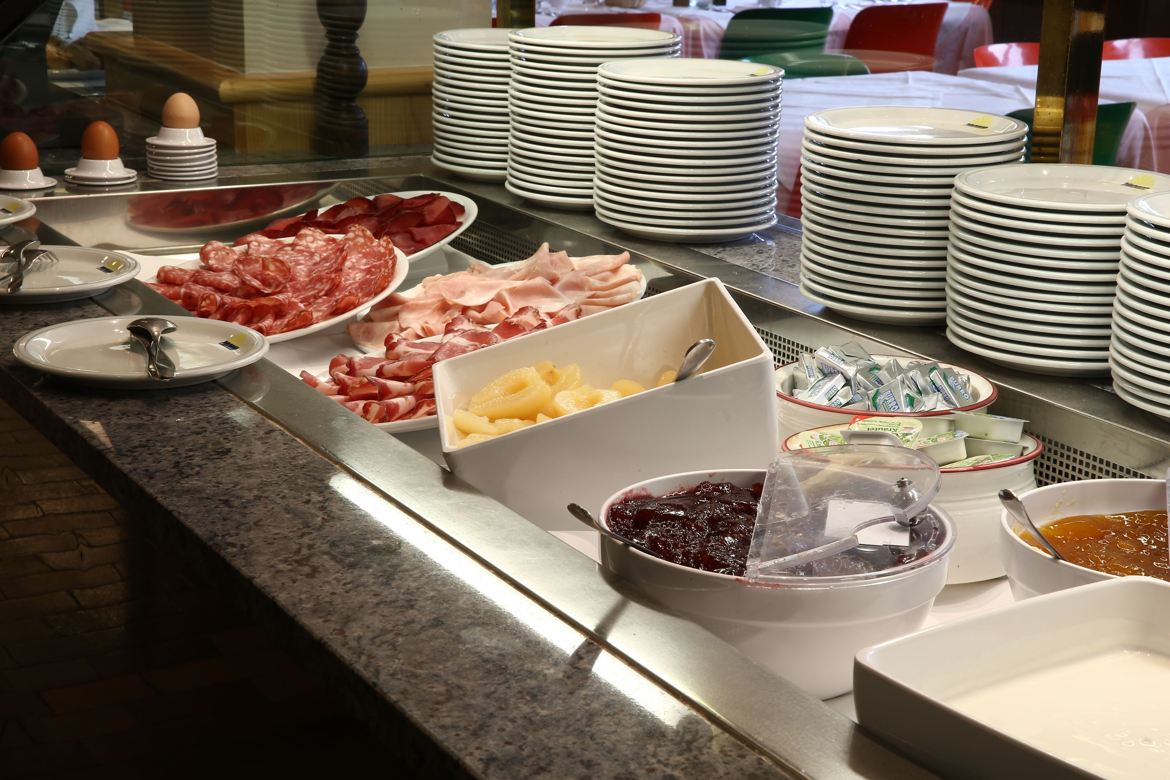 A buffet with various food items and stacked plates.