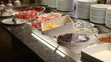 A buffet with various food items and stacked plates.
