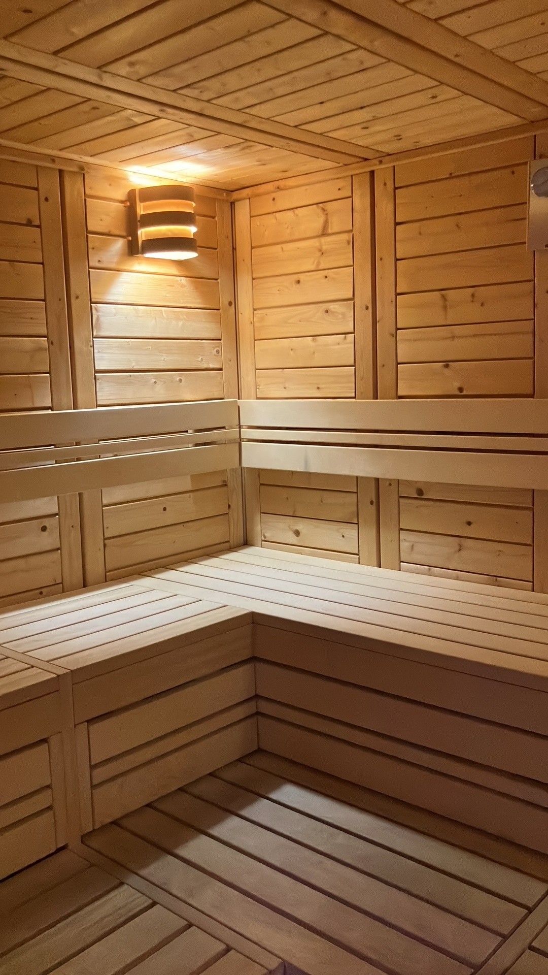 Eine Sauna mit Holzbänken und schrägverdeckter Decke.