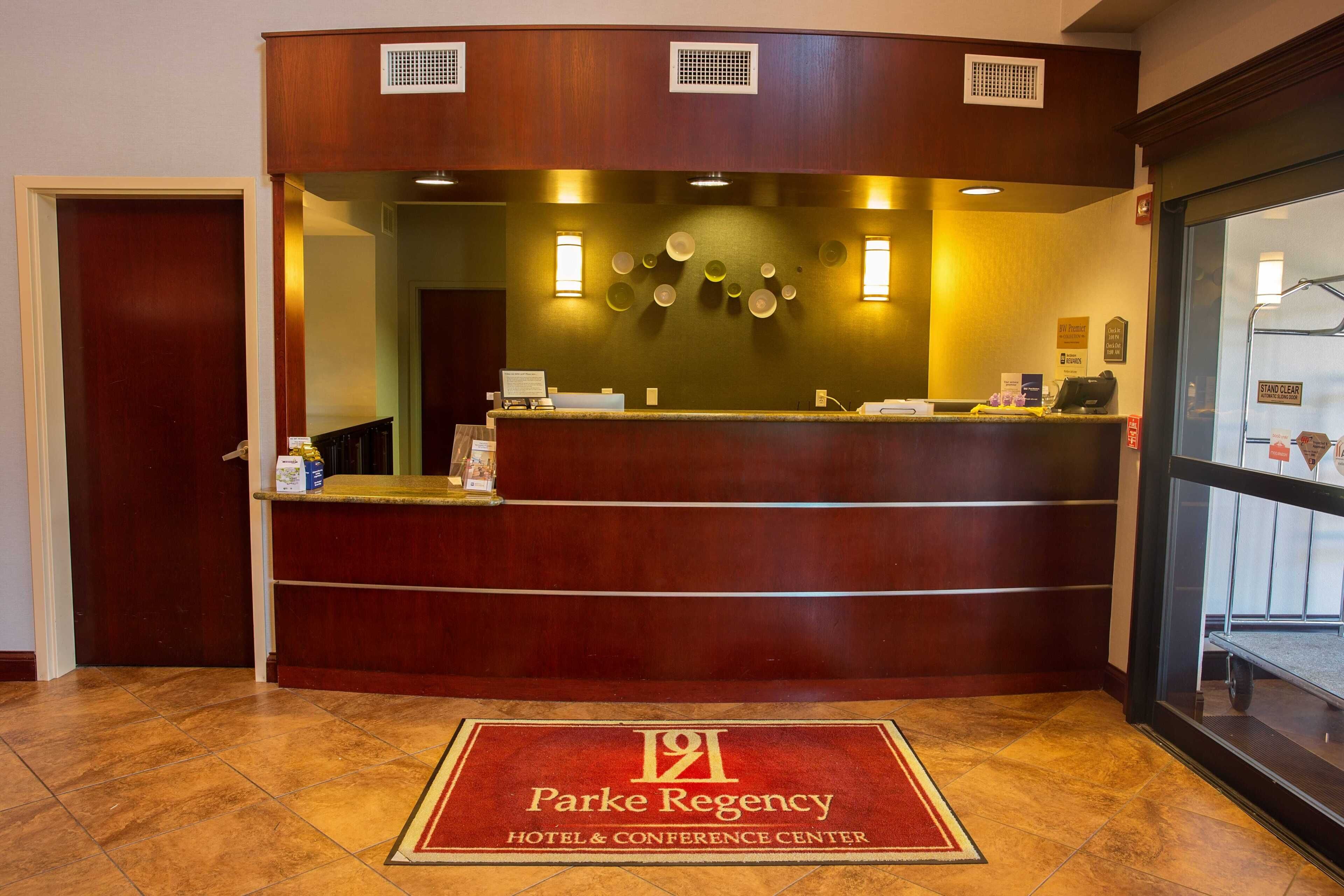 A reception desk with a logo, a 'Stand Clear' sign, and a red carpet with the hotel name.