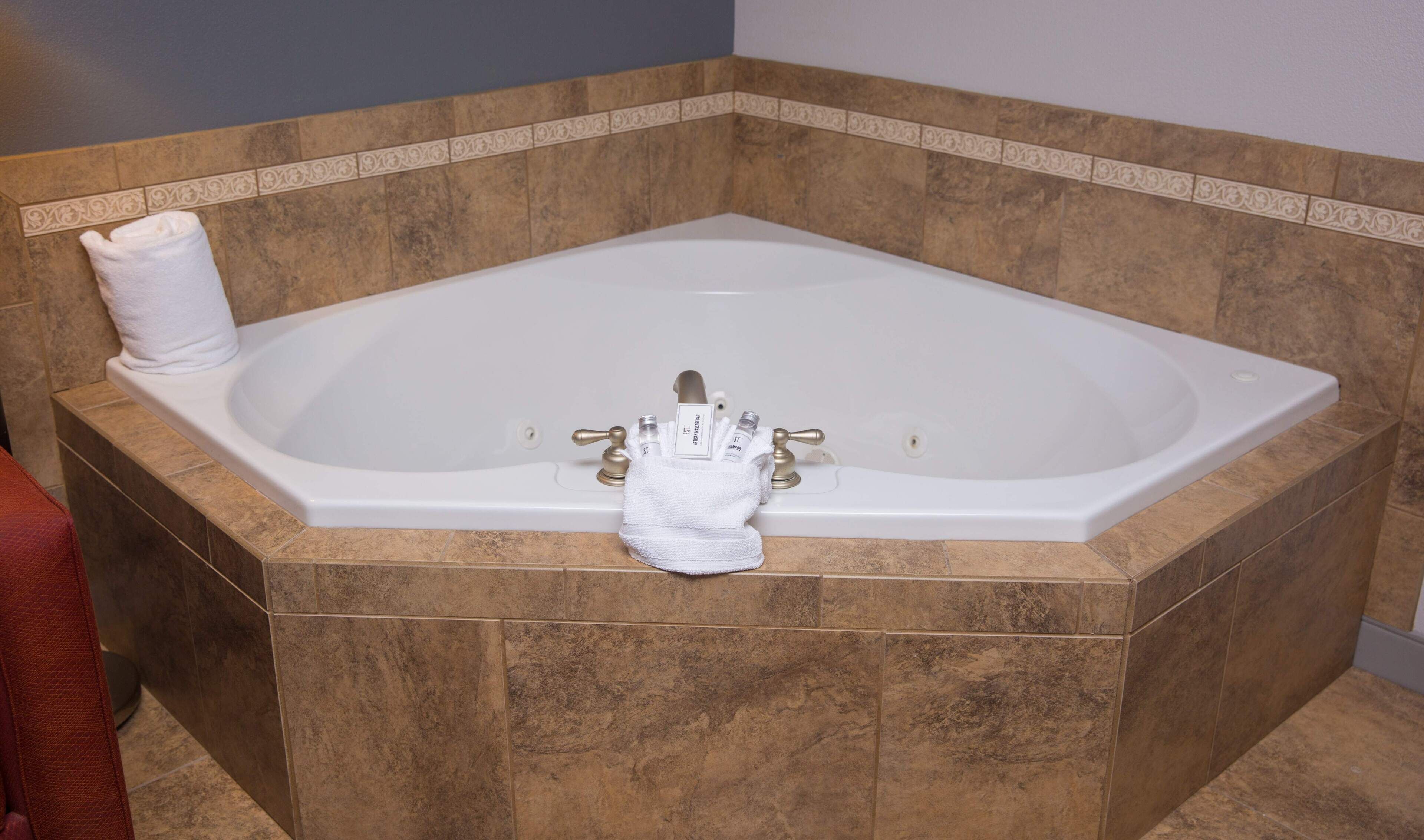 Una bañera grande y rectangular con una toalla y artículos de aseo.