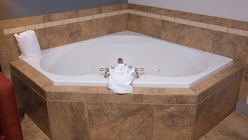 Una bañera grande y rectangular con una toalla y artículos de aseo.
