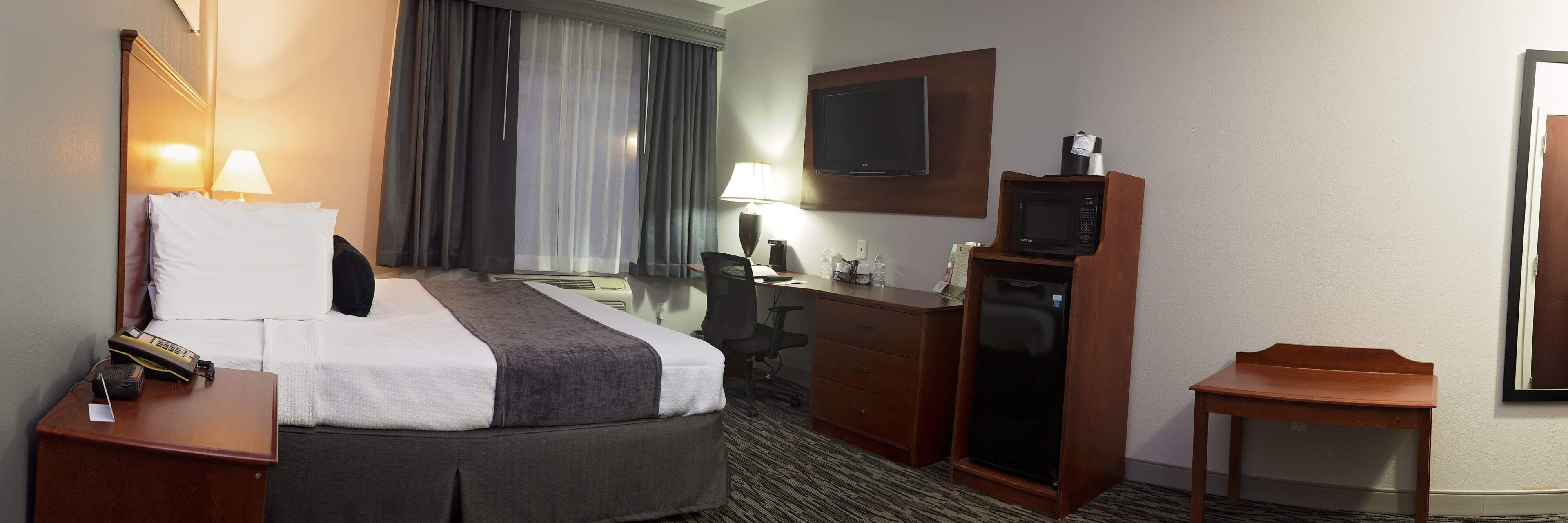 Een hotelkamer met een bed, bureau, televisie en magnetron.