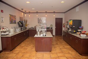 Uma cozinha de hotel com uma ilha central, uma máquina de café e um micro-ondas.