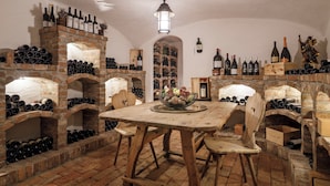 A wine cellar with brick walls, wooden tables, and numerous wine bottles.