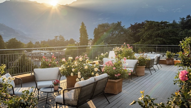 A deck with outdoor seating, potted plants, and a view of mountains.