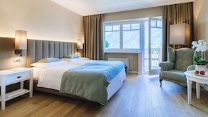 A hotel room with a bed, bedside table, lamp, chair, and a view of the outdoors.