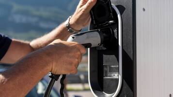 A person plugging a charging cable into a charging station.
