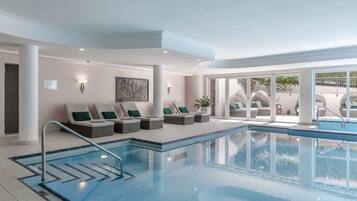 Relax by the pool surrounded by lounge chairs and large windows offering a view of the outdoors.