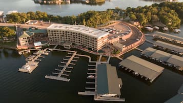 An aerial view of a waterfront hotel with a marina, multiple docks, and a large building with a curved roof.