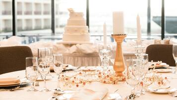 A table set for a formal event with a tiered white cake, candles, and glassware.