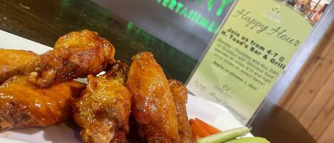 A plate of chicken wings with celery sticks on a white plate.