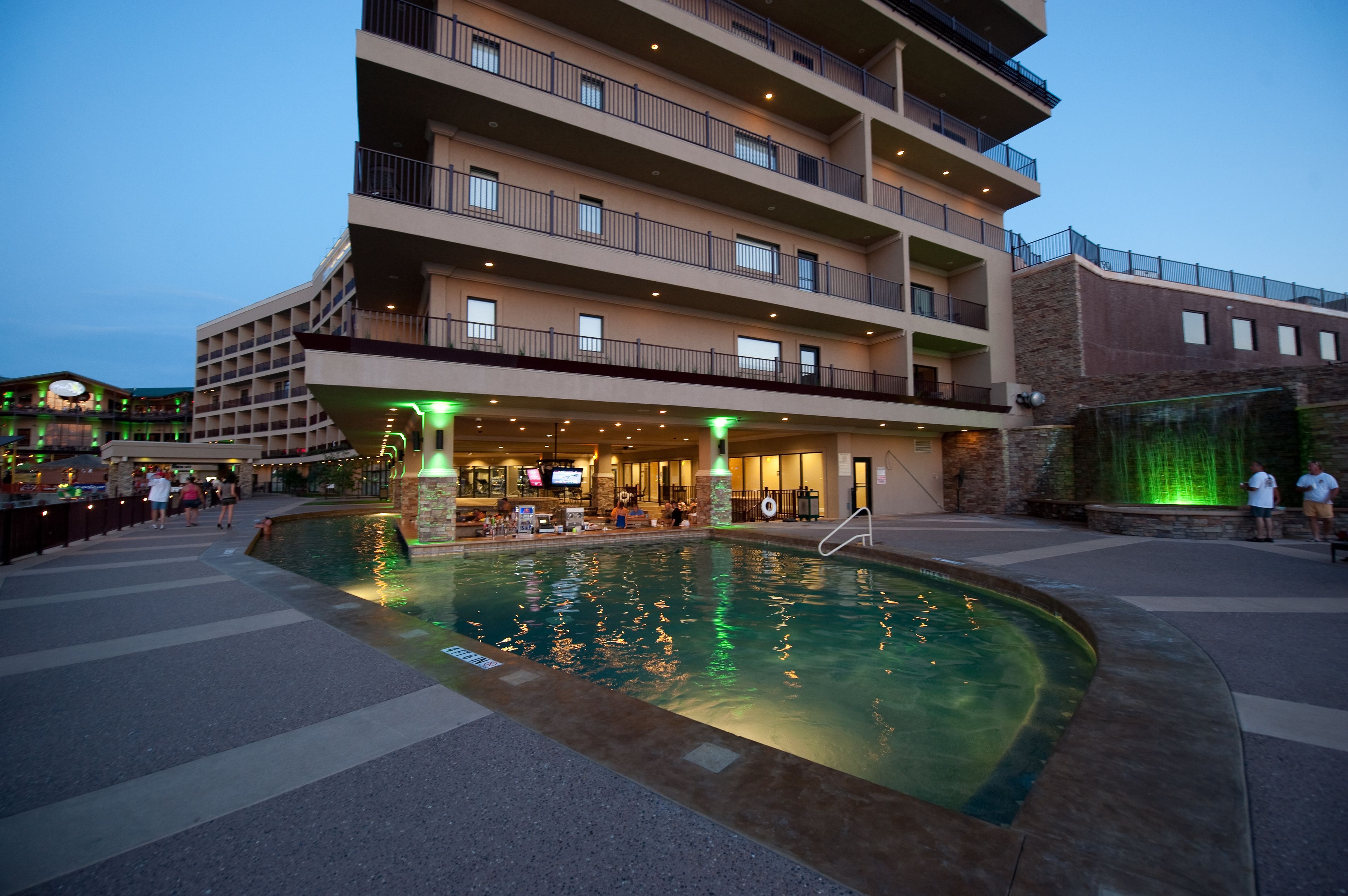 A hotel with a swimming pool, outdoor seating, and multiple balconies.