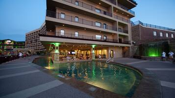 A hotel with a swimming pool, outdoor seating, and multiple balconies.