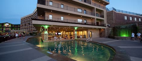 A hotel with a swimming pool, outdoor seating, and multiple balconies.