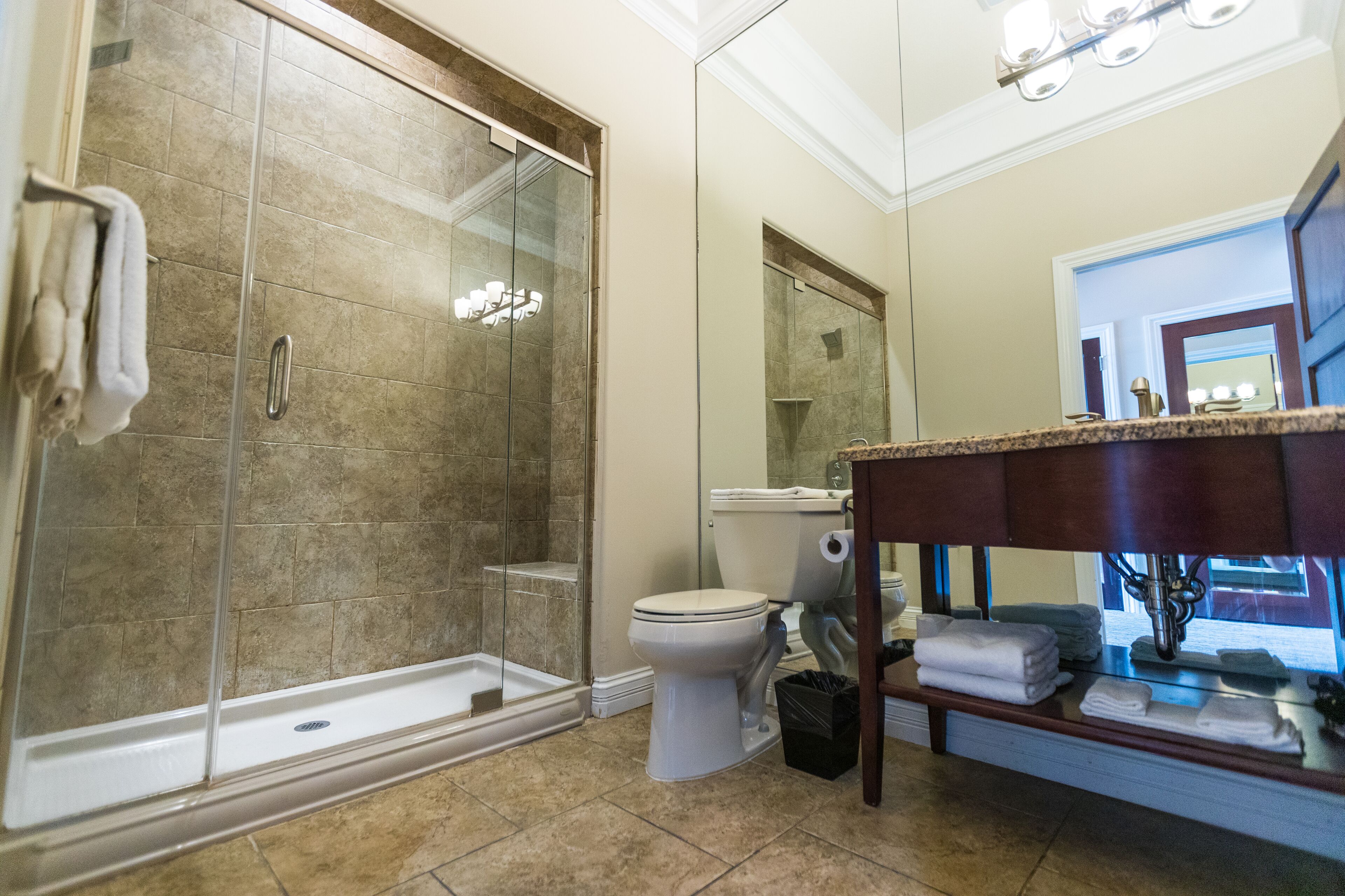 A bathroom with a glass-enclosed shower, a toilet, and a vanity with towels.