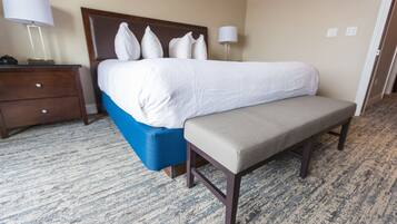 A hotel room with a bed, a bench, a nightstand, and a lamp.