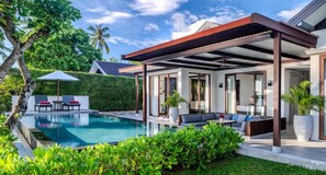 A modern outdoor pool area with a covered seating area, a pool, and lush greenery. - NH Collection Samui Peace Resort (Koh Samui)