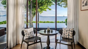 A room with a view of the sea, two chairs with patterned cushions, a round table with a teapot, and a framed picture on the wall. - NH Collection Samui Peace Resort (Koh Samui)