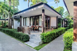 A modern house with a covered porch, steps leading to the entrance, and a garden area with neatly trimmed bushes. - NH Collection Samui Peace Resort (Koh Samui)