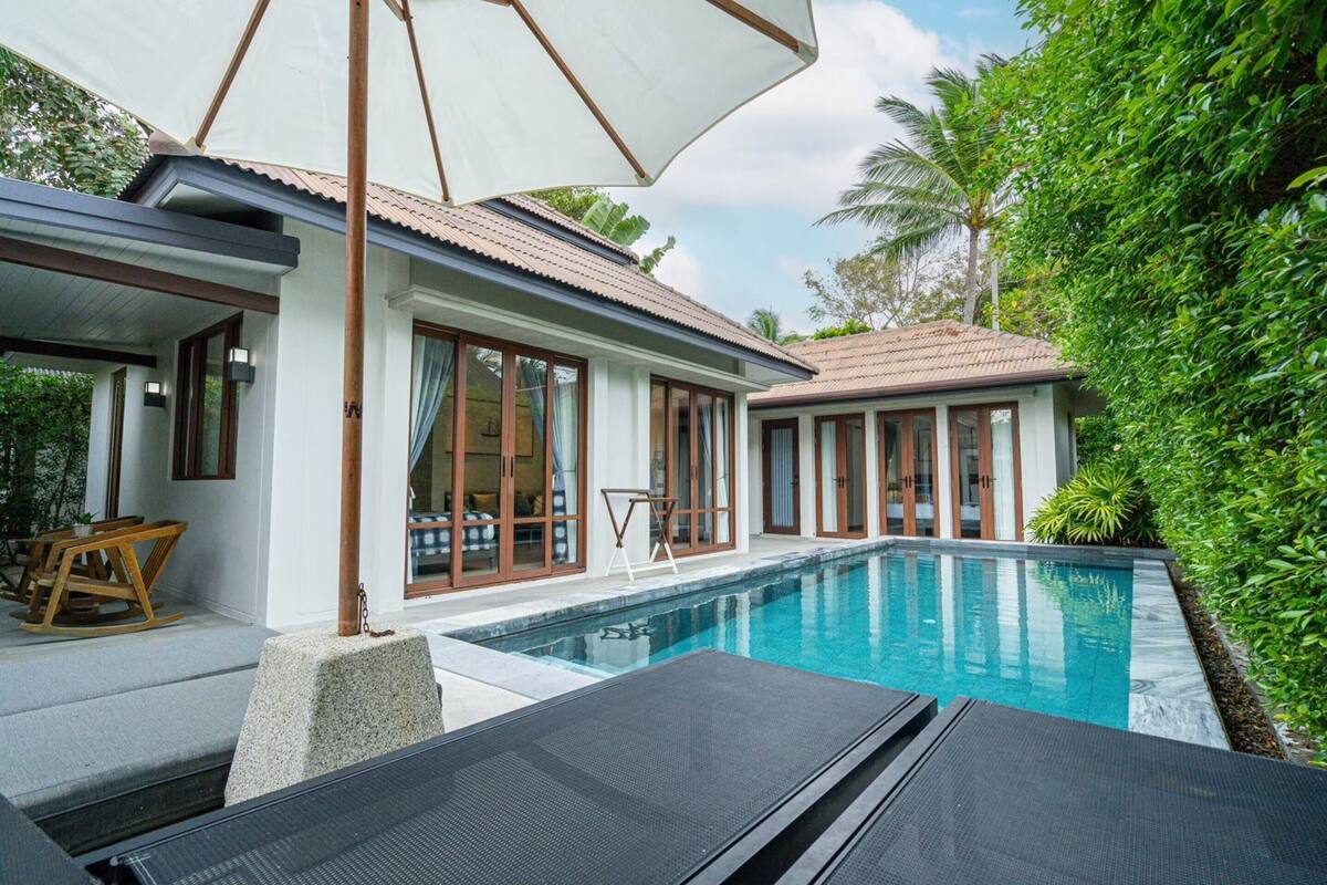 Una casa moderna con piscina, ventanas amplias y un porche cubierto.